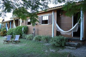 A wooden house with a porch, two lounge chairs, and a hammock.