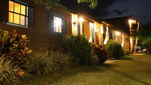 Una casa de madera con varias ventanas y puertas, rodeada de céspedes cuidados y diversas plantas.
