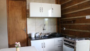 Una cocina compacta con armarios blancos, una estufa y un lavamanos.
