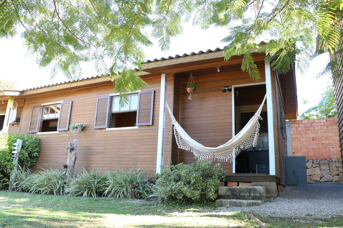A wooden house with a hammock, potted plants, and a stone wall.