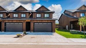 A modern two-story house with a garage, a well-maintained lawn, and a clear sky.