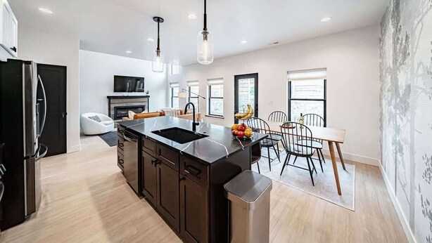 A modern kitchen with a central island, black cabinetry, and pendant lighting.