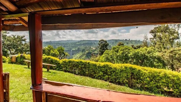 A wooden structure with a view of a lush green landscape and distant hills.