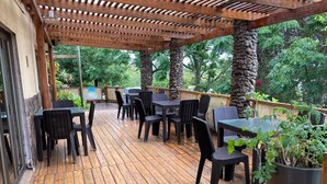 An outdoor patio with wooden flooring, black wicker furniture, and a pergola structure.