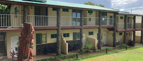 A two-story building with a flat roof, multiple windows, and a covered outdoor seating area.
