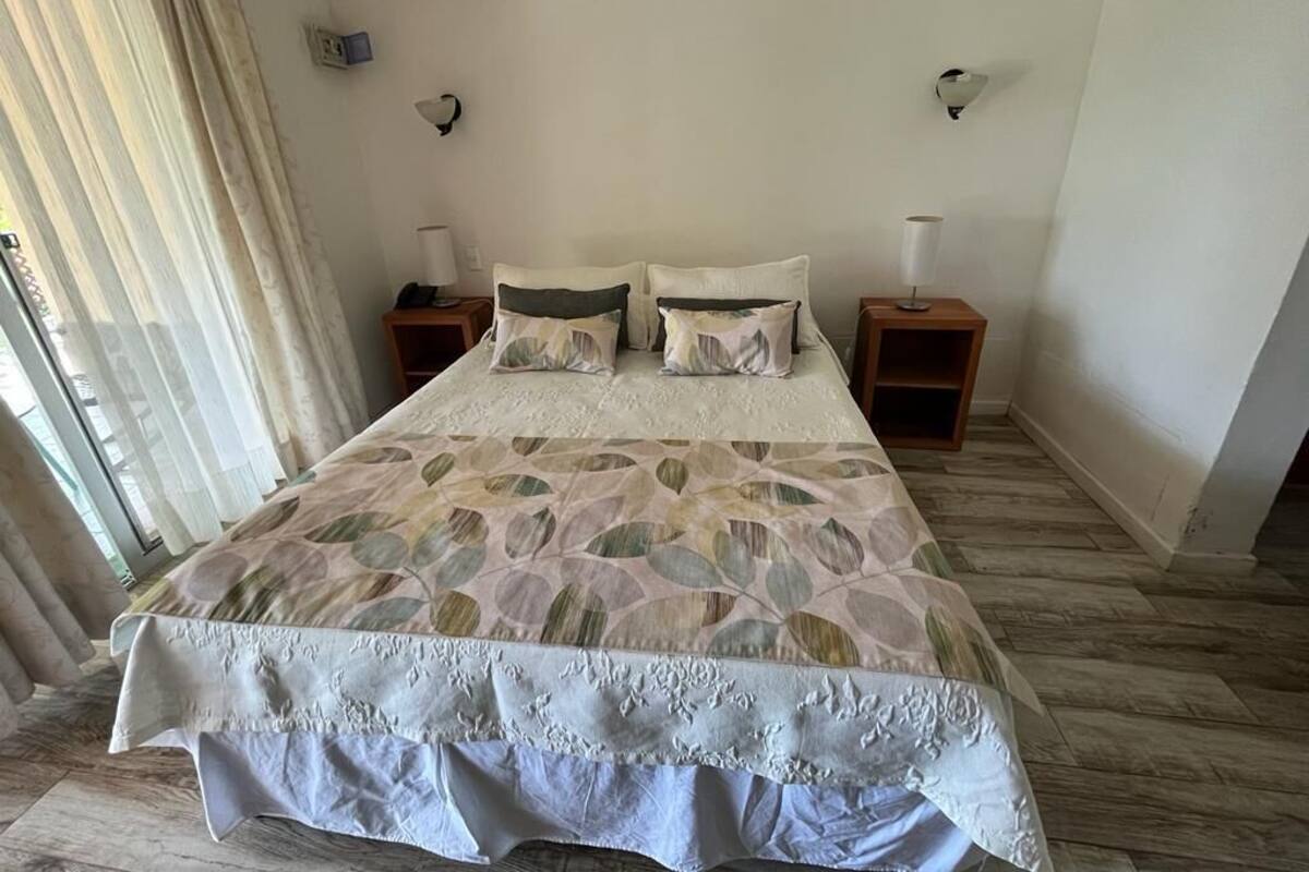 A bedroom with a large bed, two bedside tables, and a window with curtains.