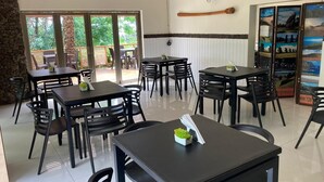 A restaurant with multiple tables and chairs, a stone wall, and a wooden bat hanging on the wall.