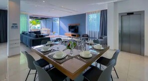 Un espace repas moderne avec une table rectangulaire dressée pour six personnes, entourée de chaises.