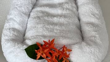 A white, fluffy, bean bag chair with a small, plush animal figure and orange flowers.