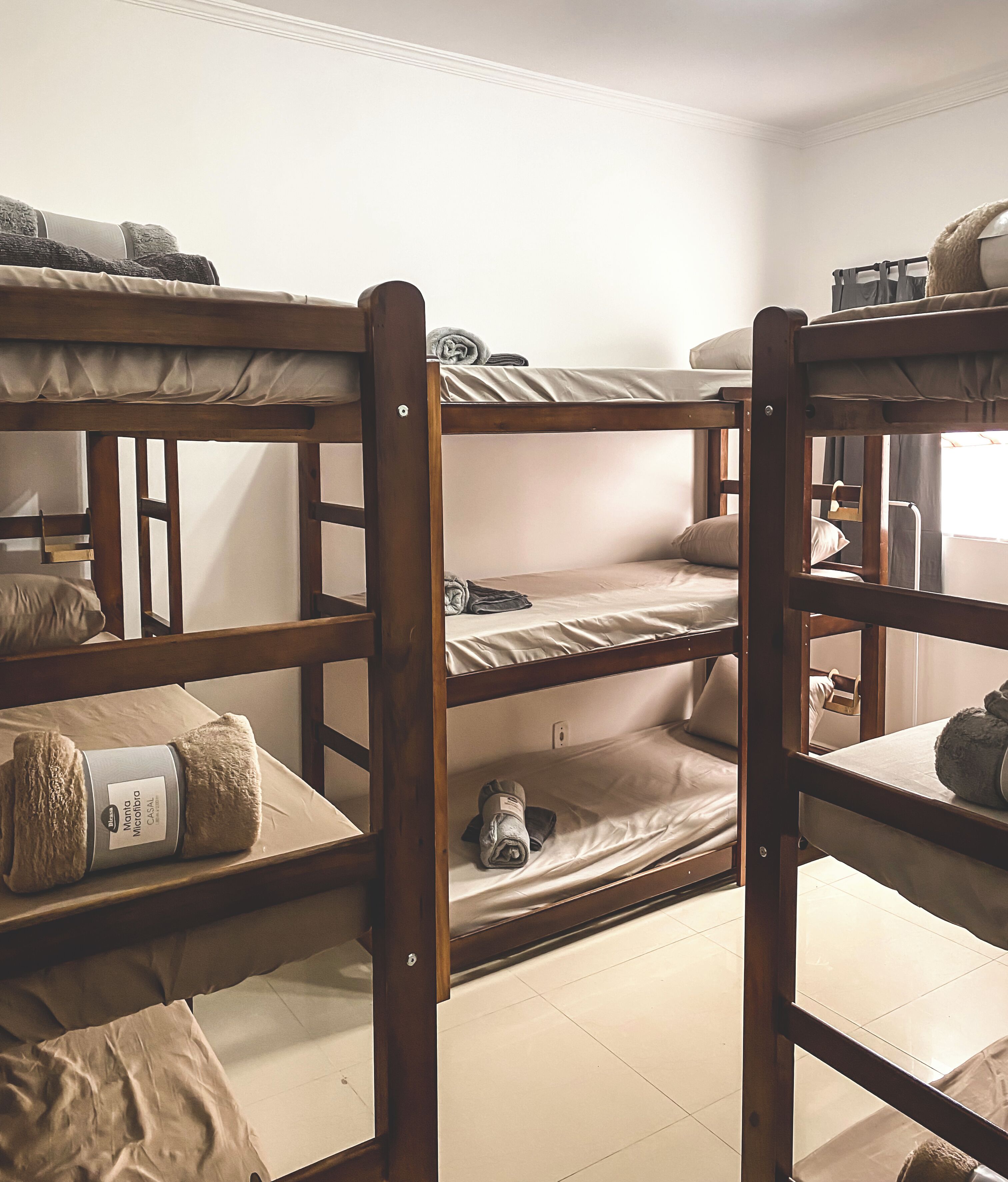 Quarto com beliche de madeira, um colchão na cama inferior e um cobertor enrolado na cama superior.