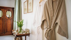 A room with a wooden wardrobe, a table with a vase and a cup, and a robe hanging on the wall. - Kolonies Tuin (Stellenbosch)