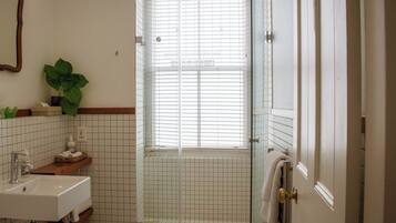 A bathroom with a sink, mirror, and a glass-enclosed shower area.