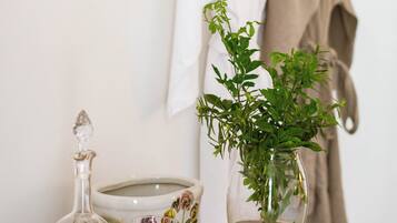Una mesa con una botella de vino, copas y un florero con plantas verdes.
