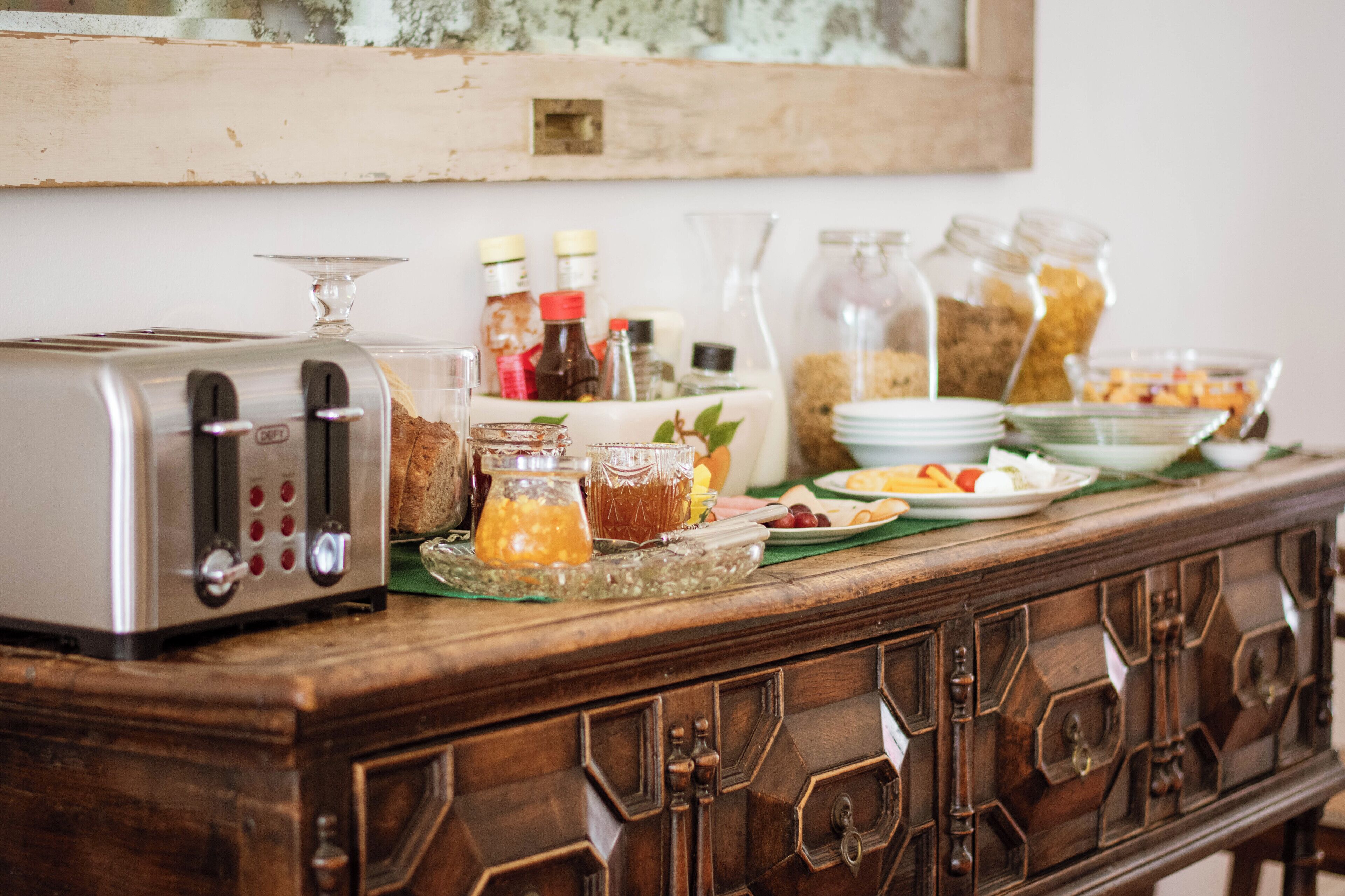 Een ontbijtbuffet met diverse etenswaren, toevoegingen en een broodrooster op een houten tafel.