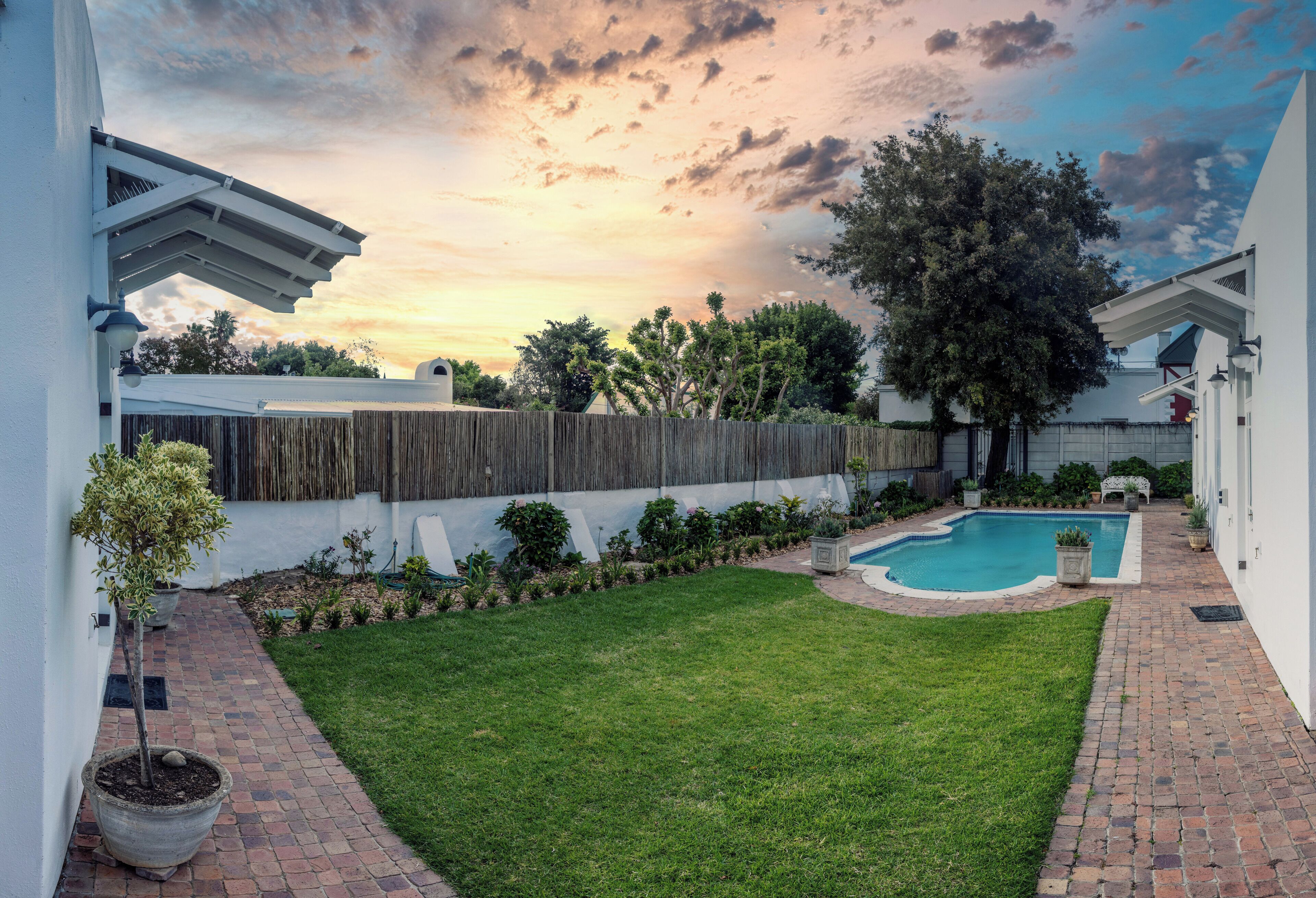 Un jardin avec une piscine, une clôture en bois et une pelouse bien entretenue.