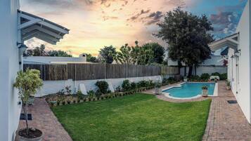 Un jardin avec une piscine, une clôture en bois et une pelouse bien entretenue.