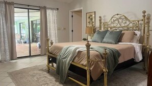 Un dormitorio con cama, cortinas, una puerta y vistas a un espacio exterior.