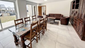Un vaste espace de vie comprenant une grande table à manger, un canapé marron et un meuble avec des tiroirs.
