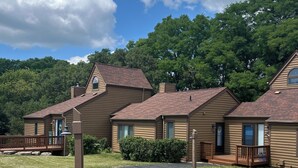 Une rangée de cabanes en bois avec des toits à deux versants, un chemin pavé et une pelouse devant.