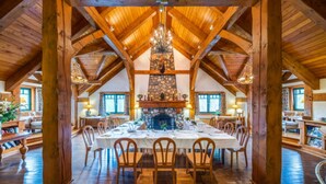 Un amplio comedor con chimenea de piedra, vigas de madera y un candelabro.