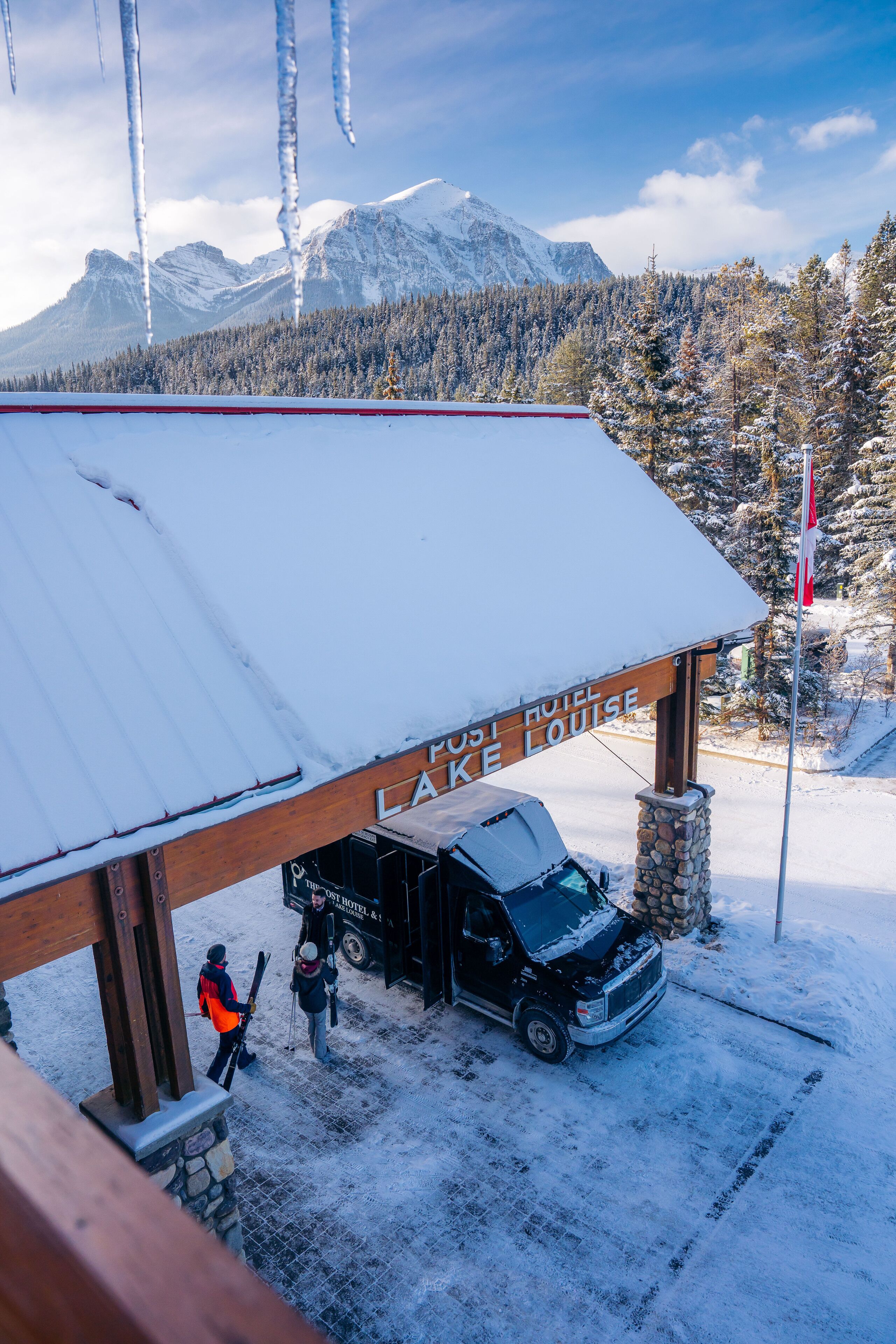 A snow-covered building with a sign reading "PUSI HOTEL LAKE LOUISE."