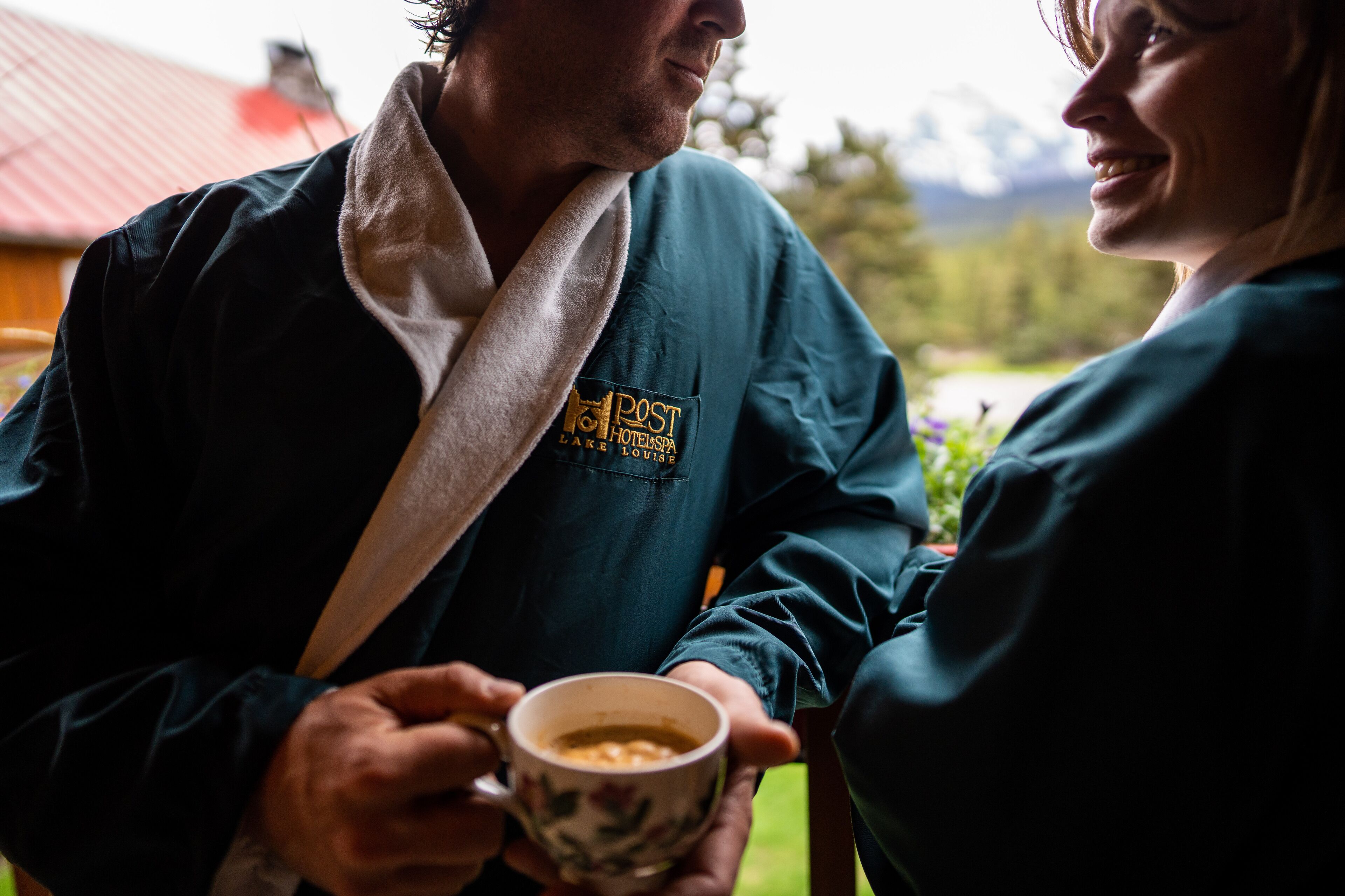 Une personne en peignoir, tenant une tasse, et le peignoir porte un logo indiquant qu'il s'agit d'un hôtel.