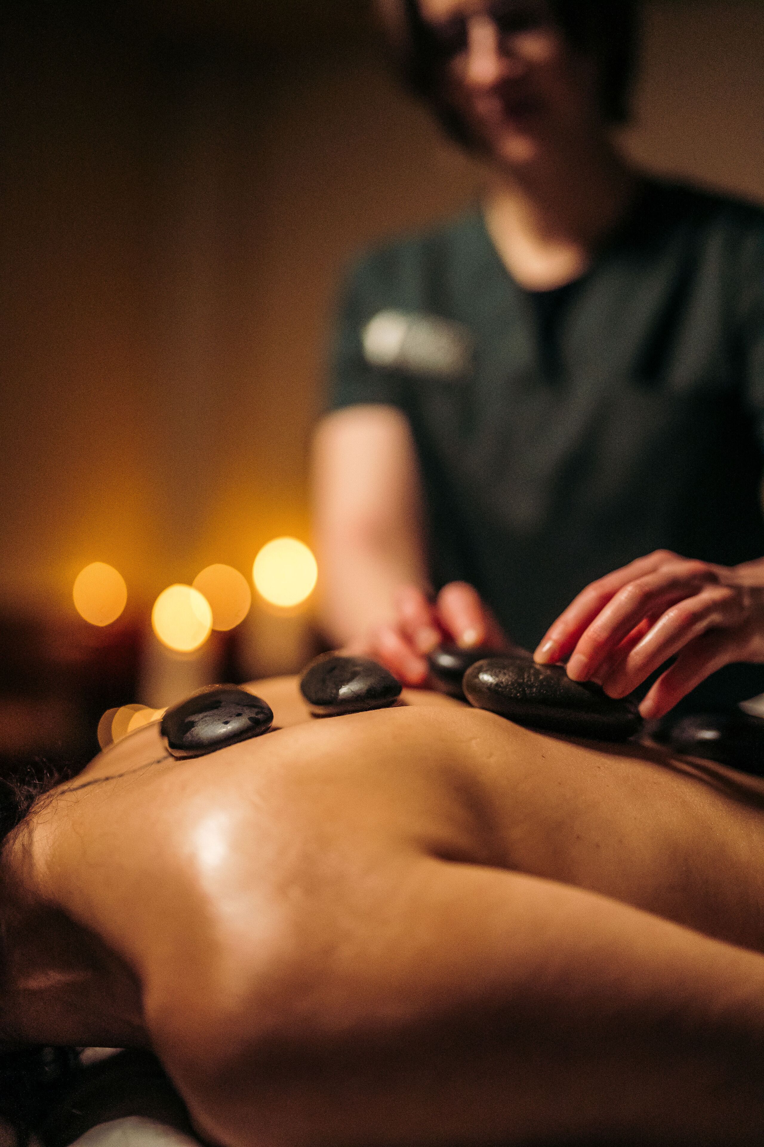 Een persoon ontvangt een steenmassage, terwijl een therapeut druk uitoefent op de rug.
