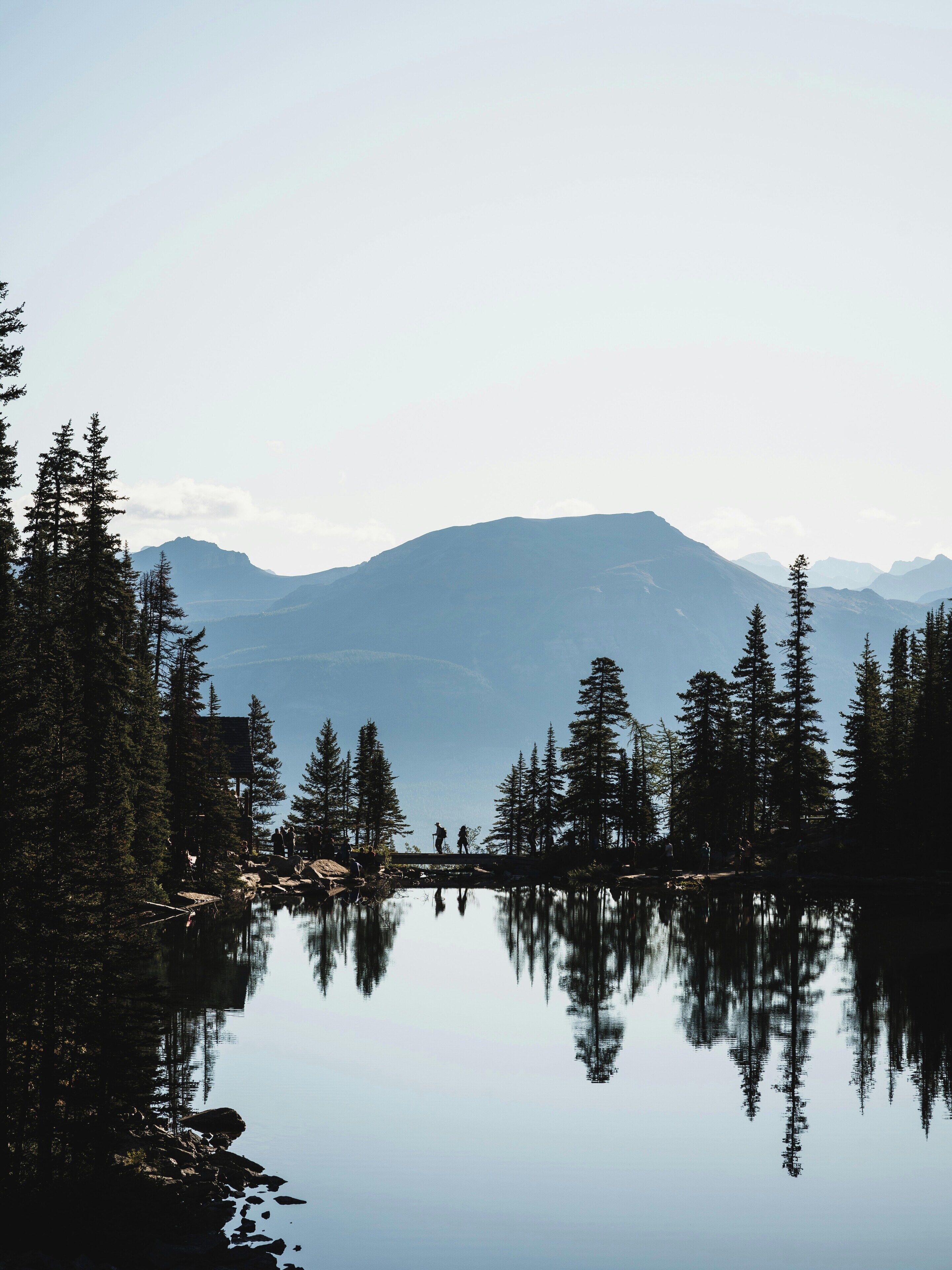 A tranquil lake surrounded by dense forest and mountains.