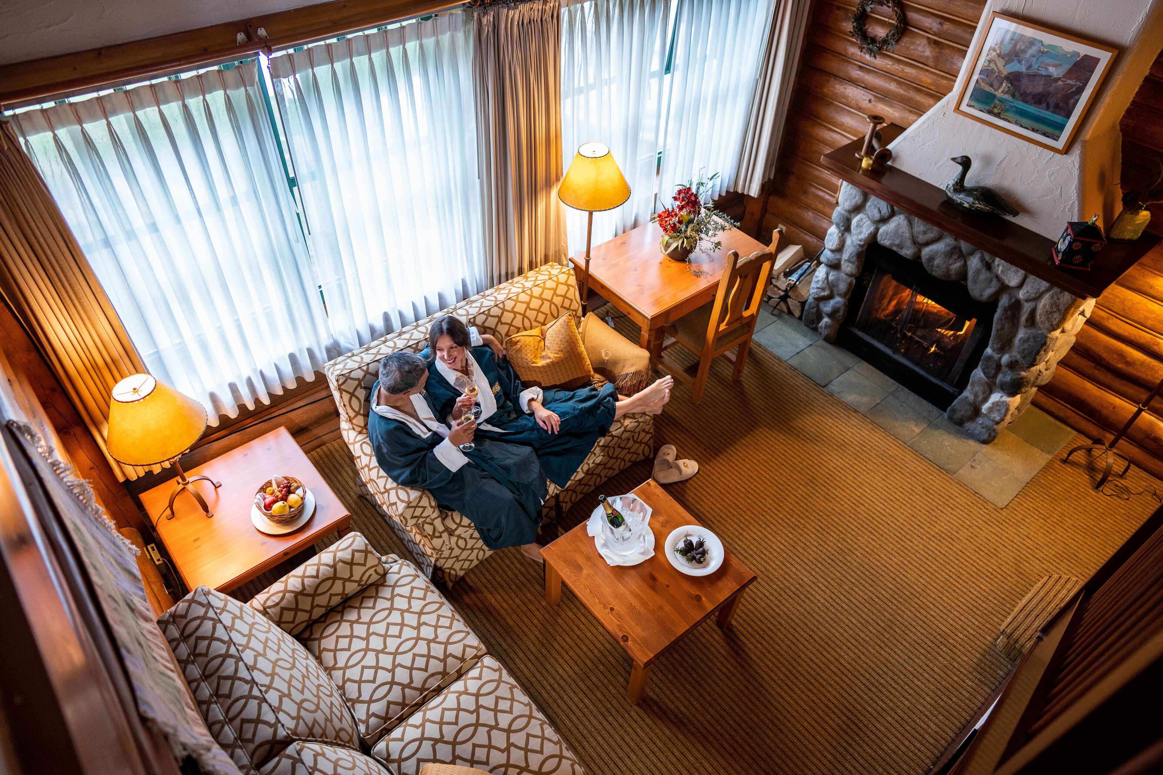 Una sala de estar acogedora con chimenea, sofás estampados, una mesa de centro y un comedor.