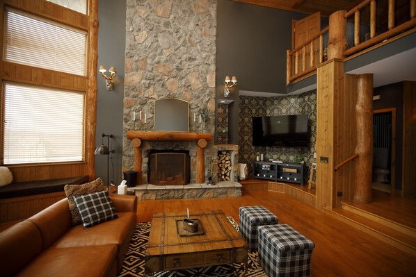 A cozy living room with a stone fireplace, wooden furniture, and a television. - Among the Trees - The Lodge (Logan)