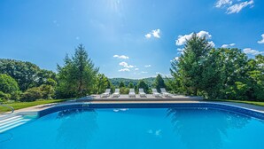 A swimming pool with lounge chairs and a view of a forested area. - Among the Trees - The Lodge (Logan)