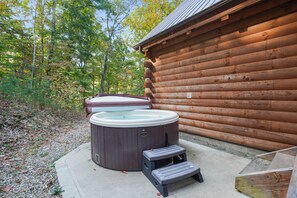 Una cabaña de madera con un jacuzzi y un escalón pequeño que lleva a él.
