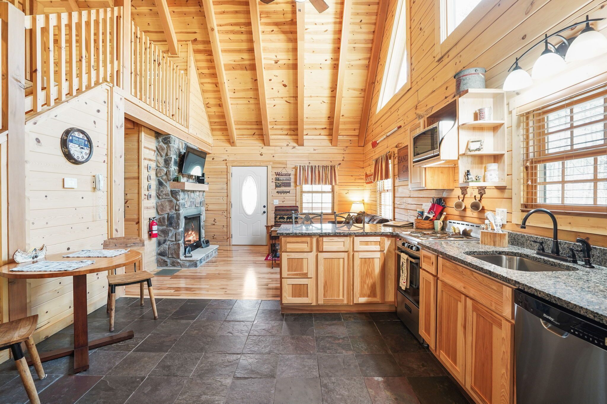 Une cuisine spacieuse avec des meubles en bois, une cheminée en pierre et un grand îlot central doté d’un évier et d’une cuisinière.