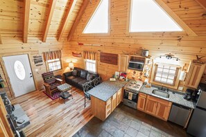Une cabane avec un intérieur en bois, une cuisine dotée de plans de travail en granit et une cheminée.