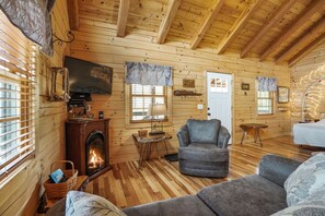 L'intérieur d'un chalet confortable, avec une cheminée, des murs en bois et un coin salon accueillant.