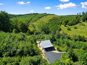 A building with a flat roof, surrounded by dense greenery and hills in the background.