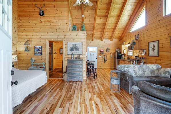 L’intérieur d’une cabane en rondins, avec un lit, un canapé, une commode et un coin cuisine.