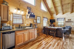 L’intérieur d’une cabane en bois comprend une cuisine, un coin repas et un salon.