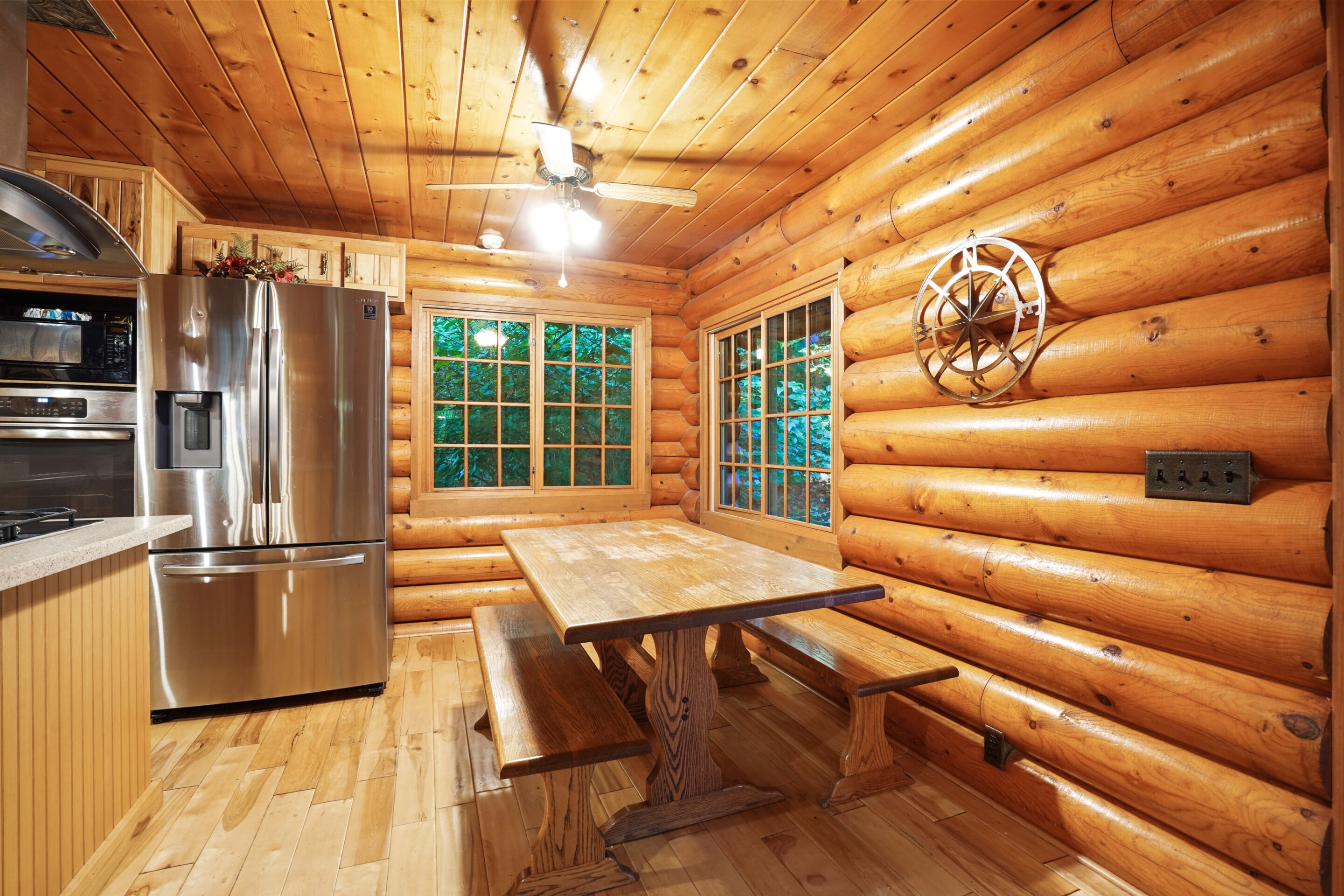 A cabin interior with a kitchen, dining area, and a large window.