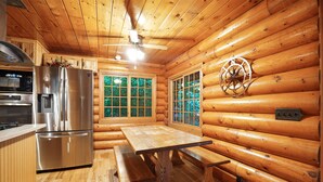 A cabin interior with a kitchen, dining area, and a large window. - Diamond In The Rough | Waterfall & Rock Wall (Rockbridge)
