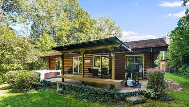 A wooden cabin with a covered patio, outdoor seating, and a barbecue grill. - Diamond In The Rough | Waterfall & Rock Wall (Rockbridge)