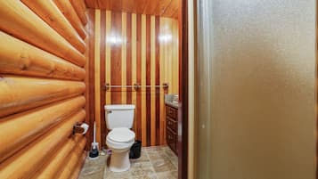 A wooden-paneled bathroom with a toilet, a sink, and a towel rack.