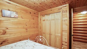 Une pièce aux murs lambrissés, contenant un lit, une armoire et un tableau accroché au mur.
