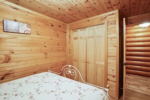 Habitació amb panells de fusta, un llit, un armari i un quadre penjat a la paret.