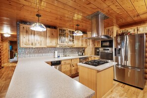 A modern kitchen with wooden cabinets, stainless steel appliances, and a granite countertop.