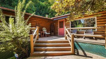 A wooden cabin with a stone staircase leading to a deck area.