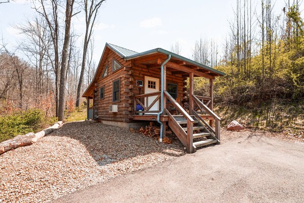 A log cabin with a porch, a staircase, and a gravel driveway. - Snuggle Bear | Hocking Hills, Adorable Tiny Home (Logan)