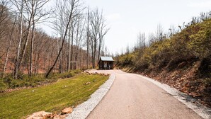 Un camino rural con una cabaña pequeña a la derecha.