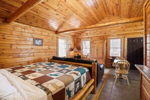 Una habitación tipo cabaña de madera con una cama, un escritorio y una silla.
