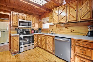 A kitchen with wooden cabinets, stainless steel appliances, and a dishwasher. - White Oak Cabin | Hocking Hills, Hot Tub, Rec Room (Rockbridge)